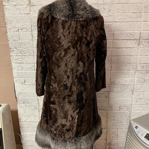 Brown vintage ILGWU winter coat with high collar and textured fur lining, made in USA, hanging on a white wall hook.