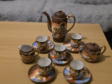 Vintage Japanese porcelain tea set with hand-painted figures and gold trim.