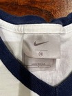 White Nike T-shirt size M with navy trim, featuring red swoosh logo and “MADE IN USA” text on white fabric tag.
