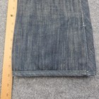 Folded blue denim Levi’s x 686 508 snowboard pants with insulated front pocket, shown on a light wood ruler.