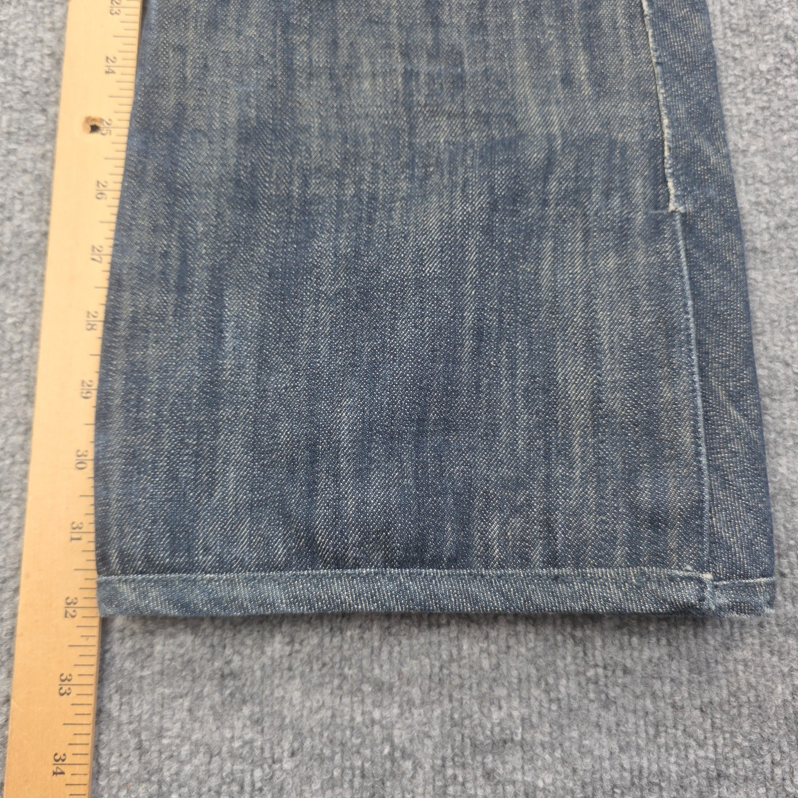 Folded blue denim Levi’s x 686 508 snowboard pants with insulated front pocket, shown on a light wood ruler.