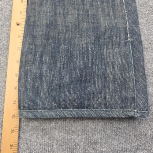 Folded blue denim Levi’s x 686 508 snowboard pants with insulated front pocket, shown on a light wood ruler.
