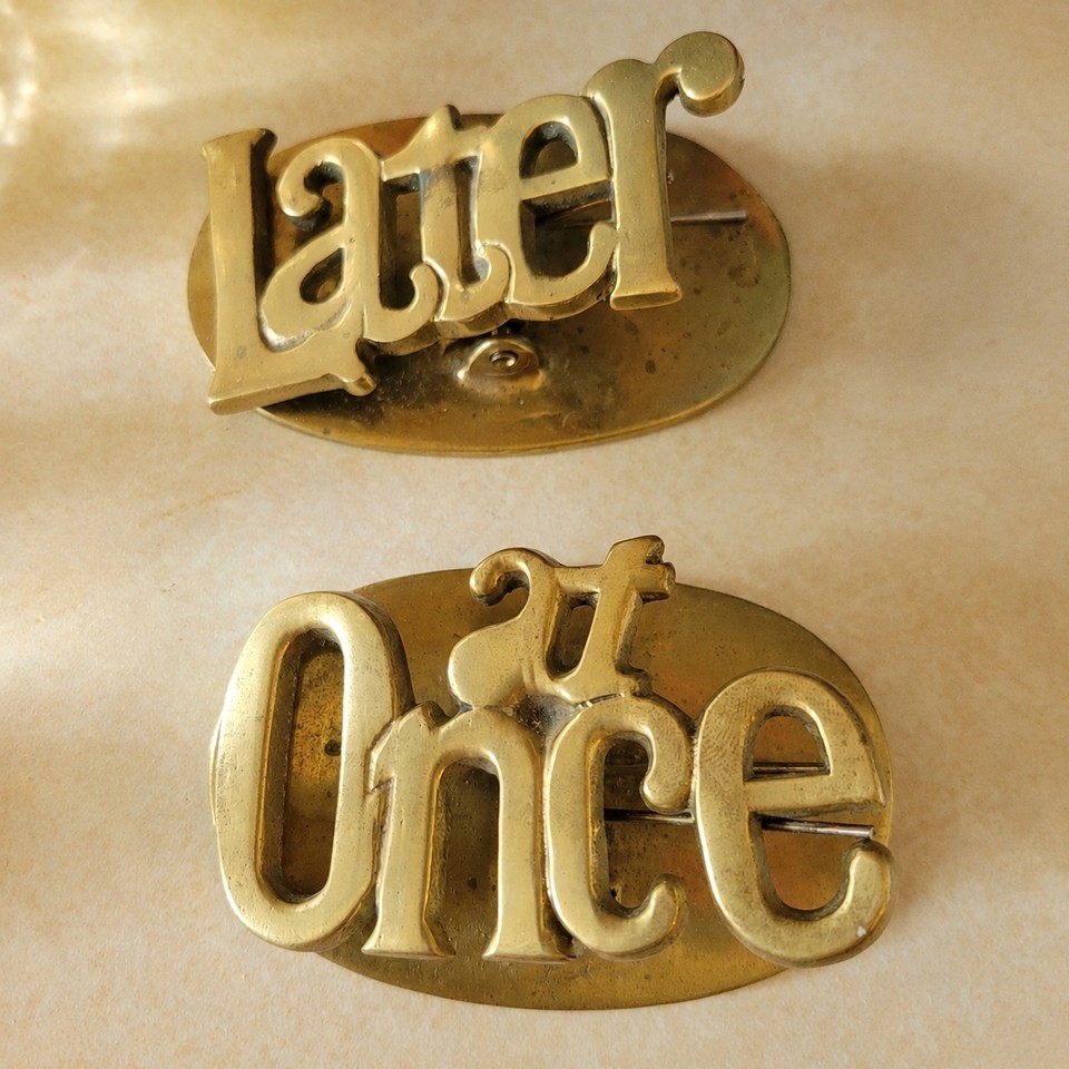 Solid brass desk clips labeled 'Later' and 'At Once' — a perfectly passive-aggressive, mid-century productivity system that's also beautiful.