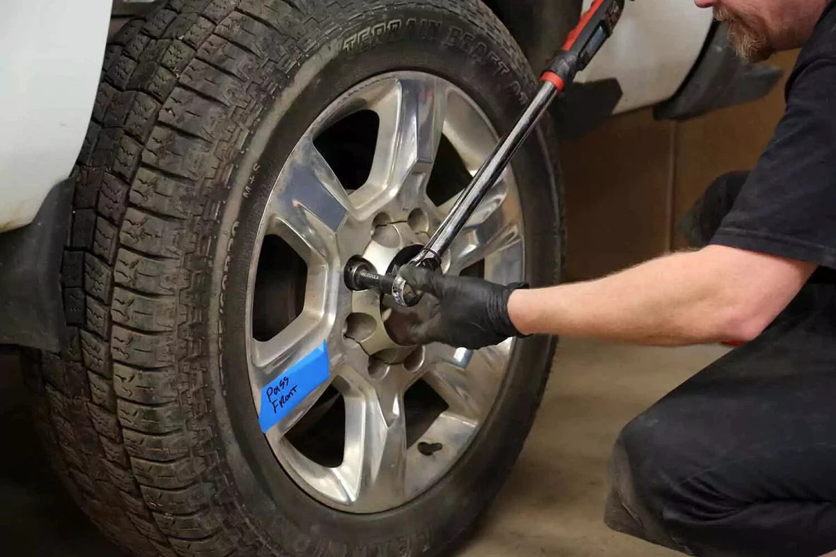 A mechanic tightens a lug nut to factory specifications with a torque wrench.