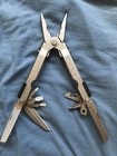 Gerber MP600 USA Made Multitool 0870314S3 with silver blades, black handles, and visible branding on blue fabric.
