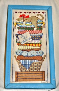 cross-stiched picture of a slumbering cat framed stitched by Joan 1991 13x7 in
