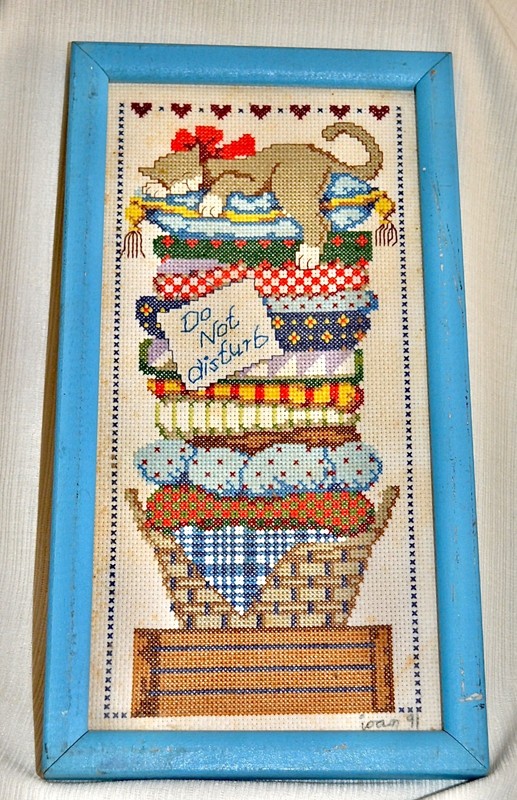 cross-stiched picture of a slumbering cat framed stitched by Joan 1991 13x7 in