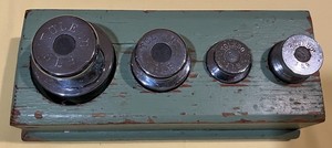 VINTAGE SET OF 4 TOLEDO CALIBRATION WEIGHTS IN EARLY PAINTED WOODEN GREEN BASE