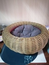 basket bed for a cat or a small dog made of artificial rattan with a pillow