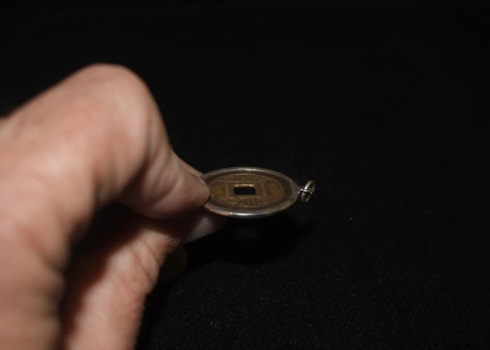Antiguo colgante de moneda china encerrado en ribete de plata con un lazo de collar Foto 2 de 4