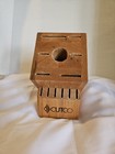 Rectangular wooden CUTCO knife storage block with 13 slots and a central circular hole, placed on a white fabric surface.