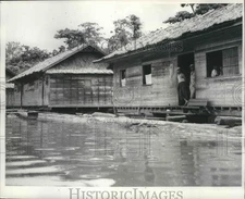 1962 Press Photo Loungers stand in door of general store and watch river traffic