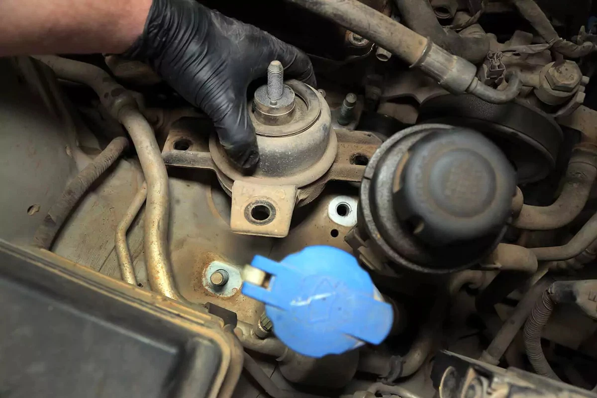 Mechanic pulling the motor mount away from the engine.