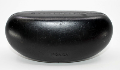 Black hard-shell Prada eyewear case featuring an embossed logo