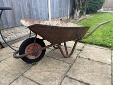 OLD WHEELBAROW RUSTY USE FOR A PLANTER OLD CONCRETE INSIDE