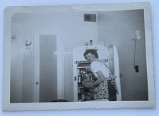 Instantánea vintage de los años 50: sincera ama de casa de mediados de siglo en delantal de lunares en Refri