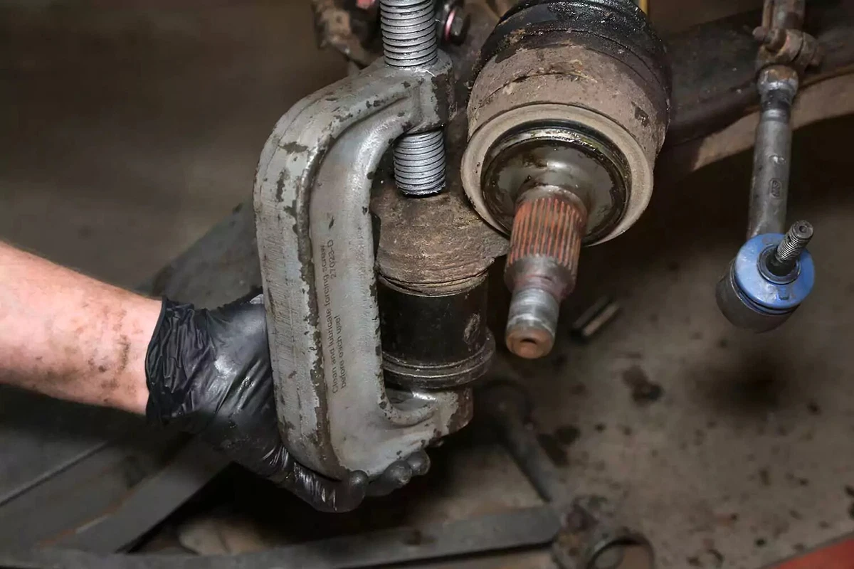 A mechanic uses a ball joint press to remove the lower joint.