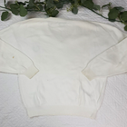 White VTG Christian Dior men's V-neck sweater with long sleeves and crew neckline, made in USA, on floral fabric background.
