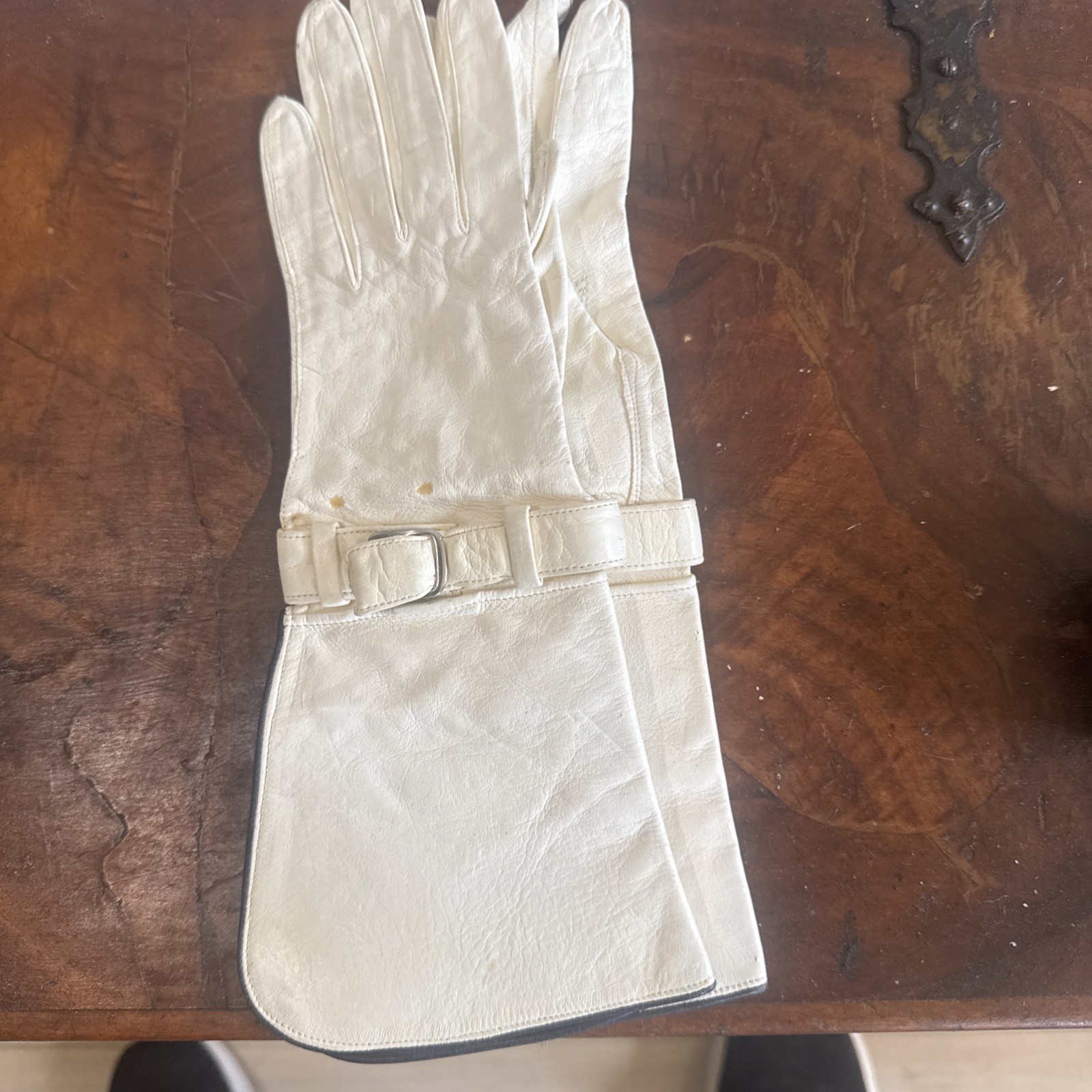 White leather gauntlet driving glove with a bow buckle.