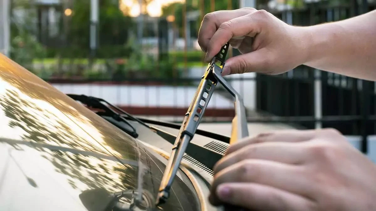A motorist carefully lowers the wiper arm to the windshield.
