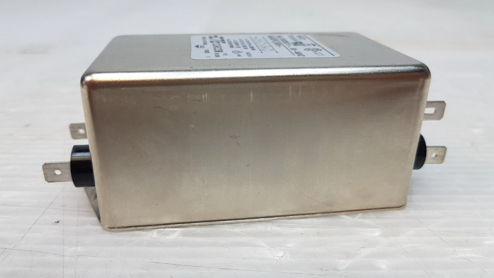 Side of the TE Corcom 16EQ1 filter metal case with tabs at both ends