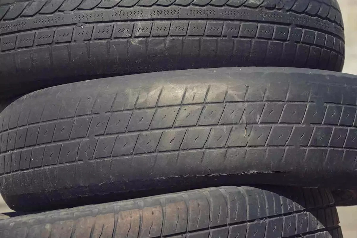 Three old tires in a stack. The center tire shows evidence of underinflation, with excess wear on the inside and outside edges.