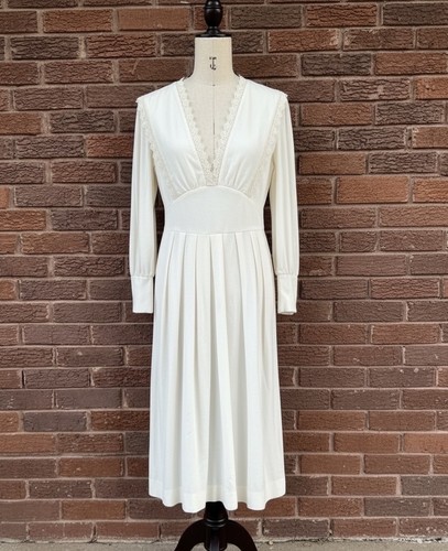 White vintage 70s midi prairie dress with scalloped lace neckline, fitted bodice, and flared sleeves displayed on mannequin.