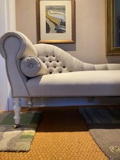 Small elegant chaise longue sofa seat covered in linen fabric with wooden legs