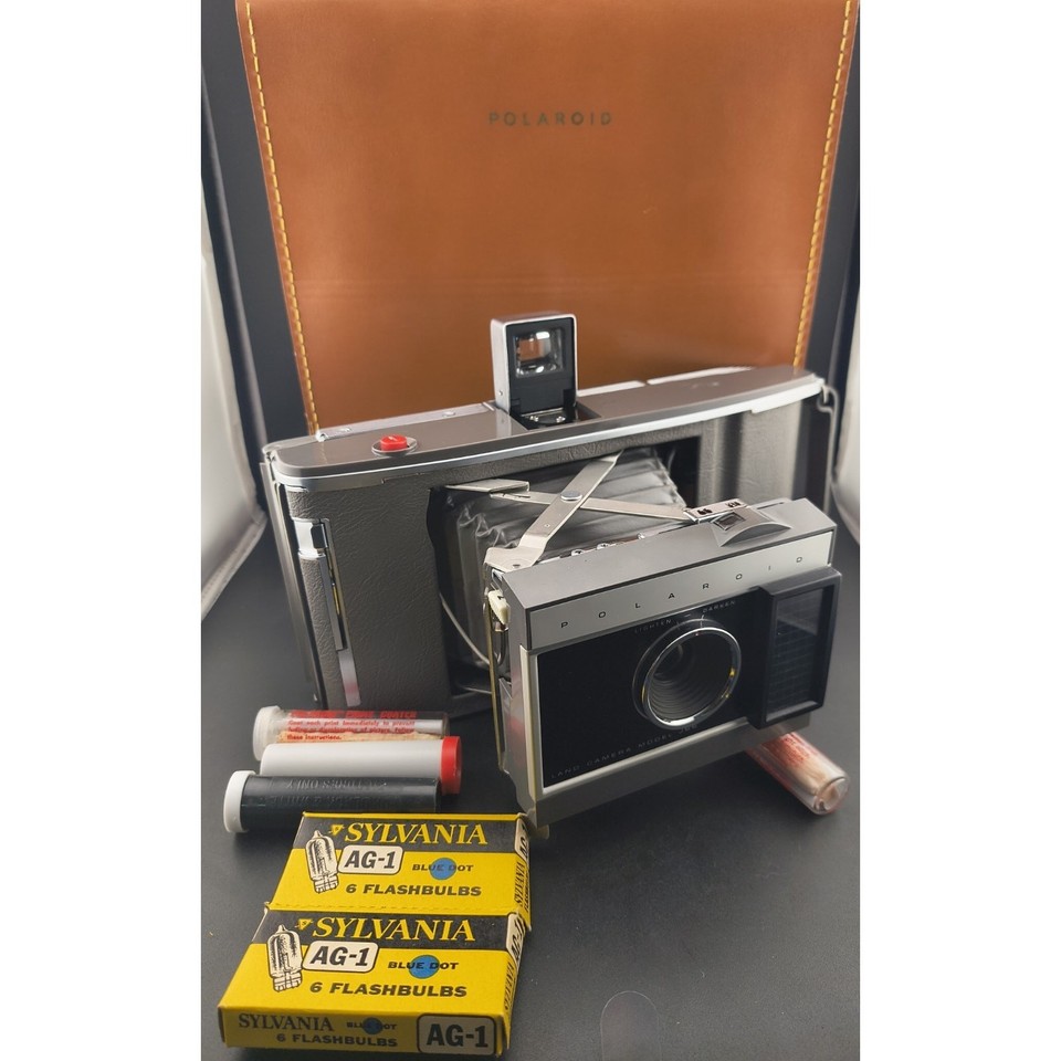 A complete, pristine Polaroid J66 pack-film camera bundle with case and accessories — a mid-century folding beauty that's as displayable as it is shootable.