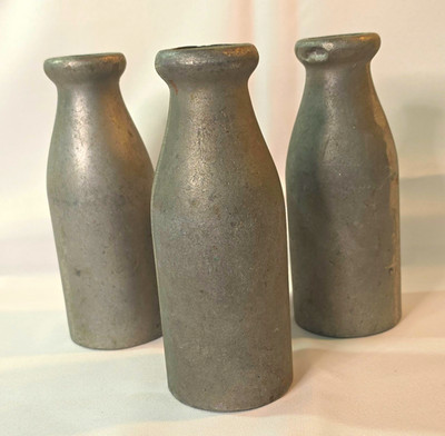 These items are vintage cast aluminum/metal milk bottles used in carnival games