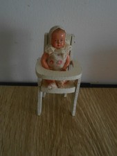 Petite poupée en celluloid sur sa chaise haute en bois