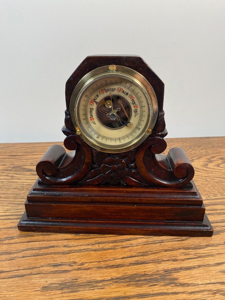 A fully exposed skeleton aneroid barometer in ornate wooden mounting — equal parts scientific instrument and Victorian conversation piece.