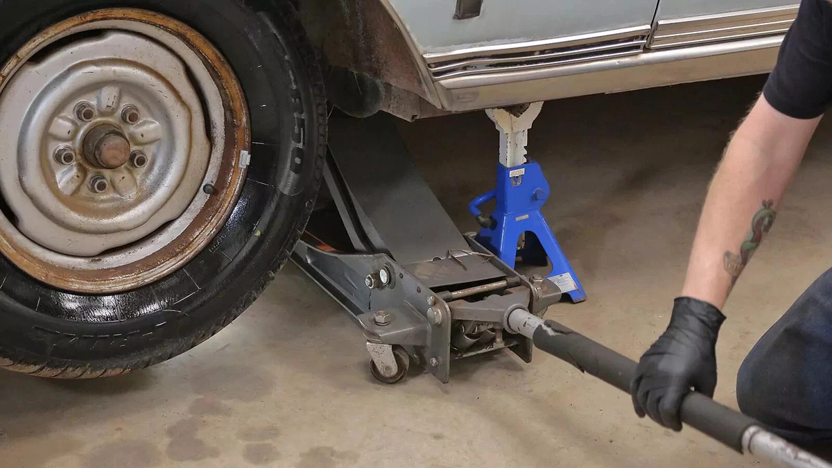 A mechanic lifts a truck with a floor jack and jackstands.