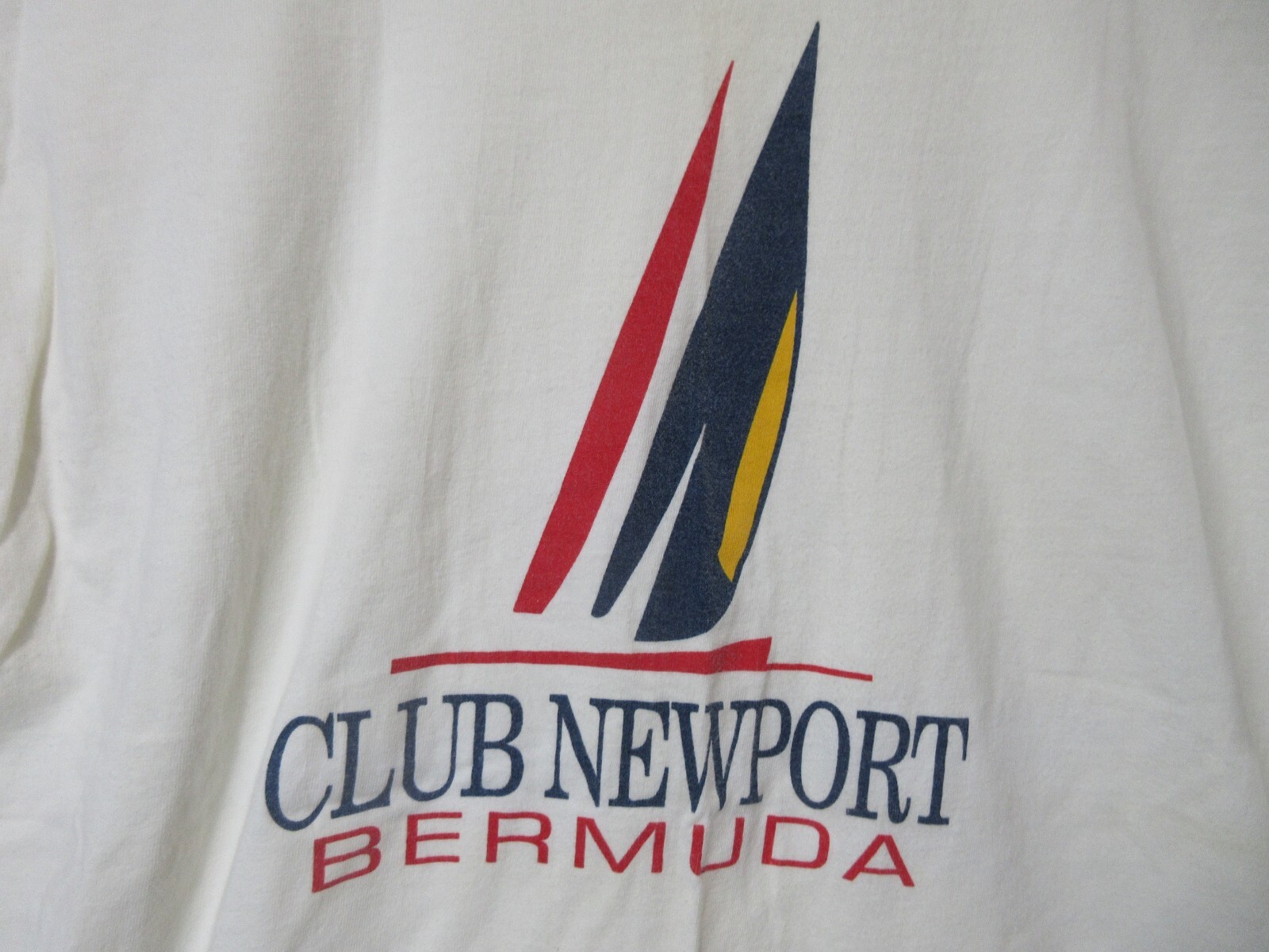 White short-sleeve shirt with black and red Sz L Vtg Bermuda Club Newport logo and navy text reading “Club Newport Bermuda.”