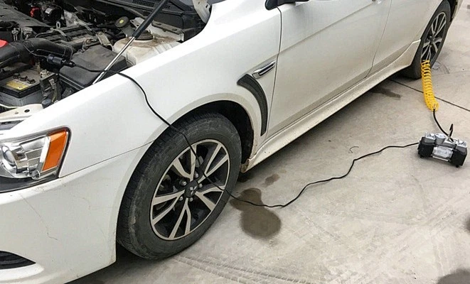 A car with a portable tire pump connected to the battery