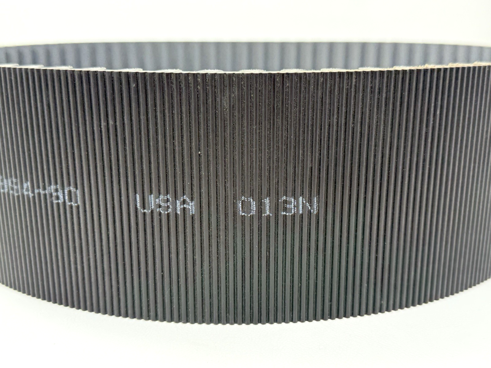 Black GATES 14MGT-994-90 poly chain belt with vertical ribbed pattern, white printed text reading “USA 013N” on black.