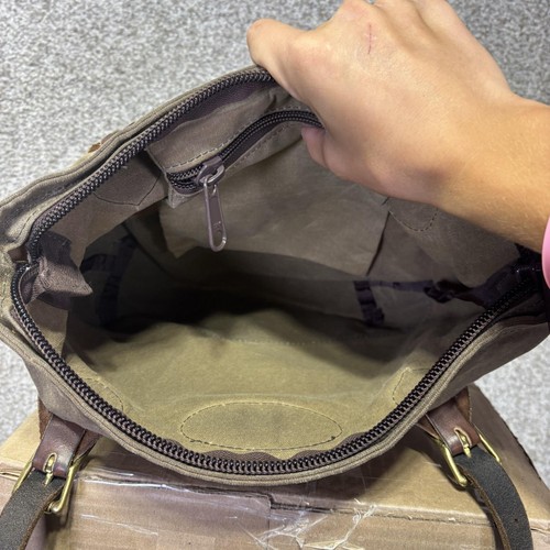 Brown canvas crossbody bag with black leather trim, open to show front zipper pocket and stitched seams.