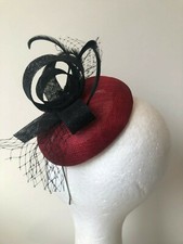 New red sinamay fascinator with black loops and feathers on a headband 