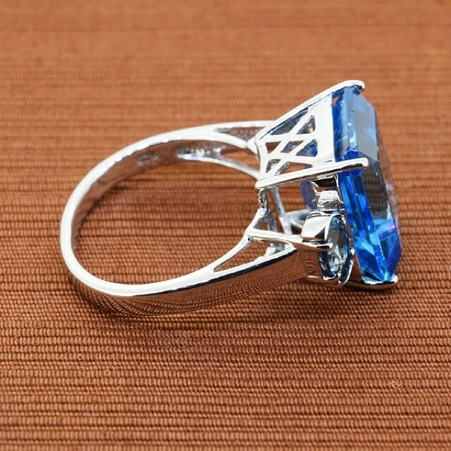 Anillo rectangular de tres piedras con topacio azul suizo profundo de 15,49 quilates corte escalonado y corte ovalado Foto 4 de 4