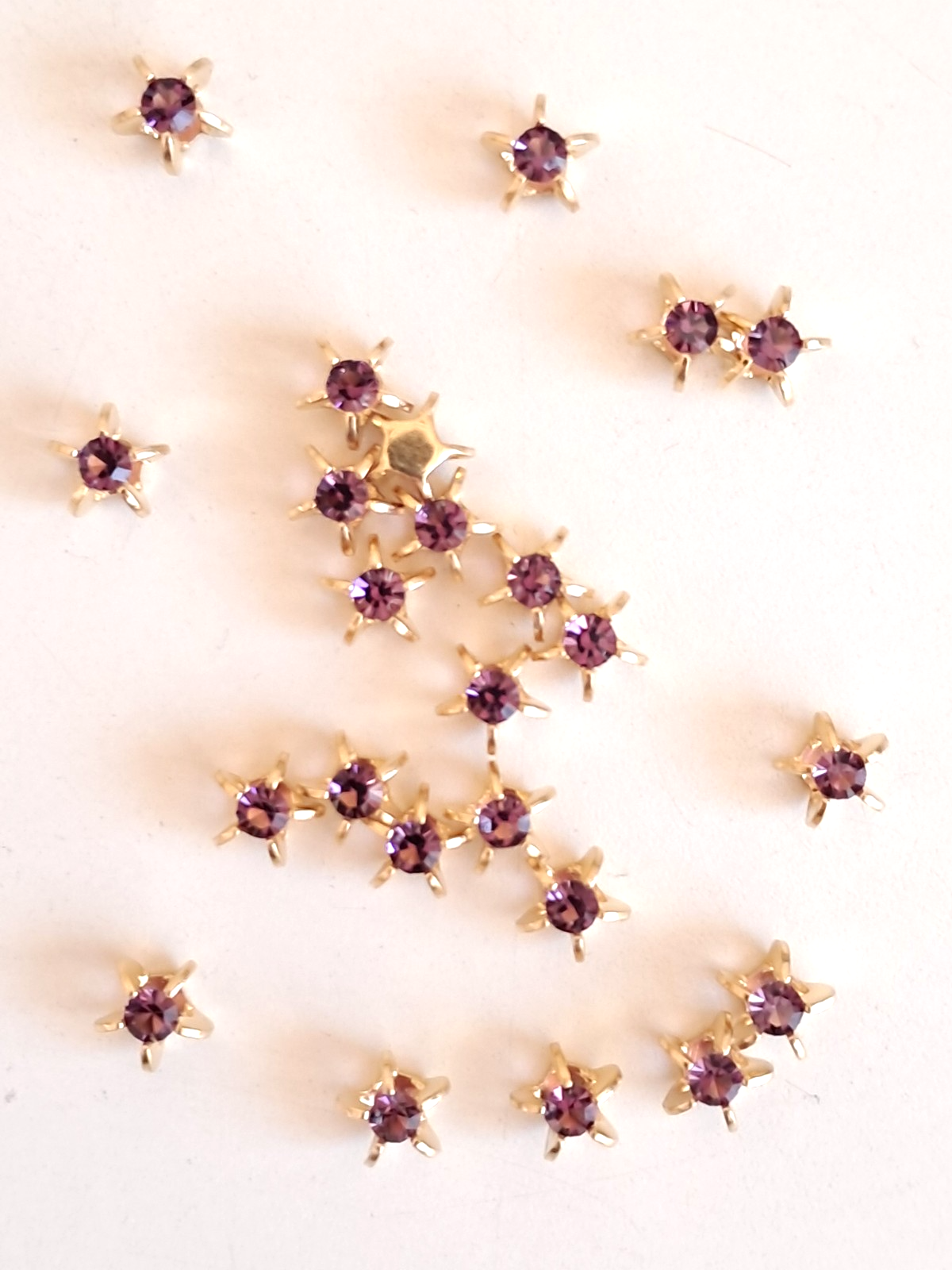 SWAROVSKI, 24 PIECES, AMETHYST STARS, IN BRASS SETTINGS