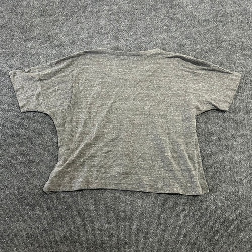 Grey cropped The Beatles T-shirt with long sleeves, shown from the back on a textured gray surface.