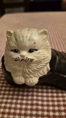 vintage ceramic figurine featuring a white cat nestled inside a black shoe.
