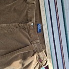 Brown corduroy pants with white Polo Ralph Lauren label, button closure, and straight hem, laid flat beside a 12-inch ruler.