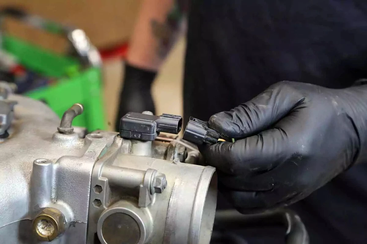 A mechanic removes the throttle body electrical connection.