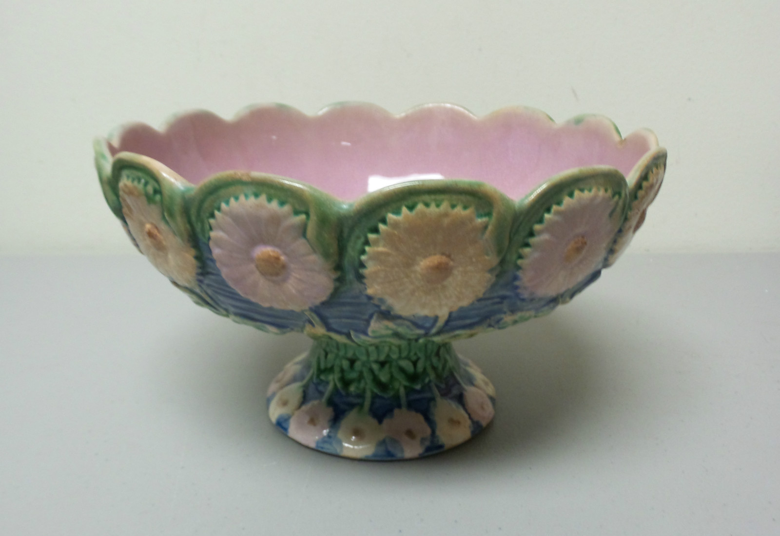 Antique Etruscan majolica compote with a daisy motif in cream, green, and brown glaze.