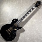 Black Epiphone LP Custom electric guitar with gold hardware, white fret markers, and a glossy finish on a light background.