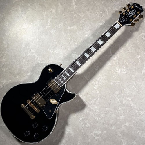 Black Epiphone LP Custom electric guitar with gold hardware, white fret markers, and a glossy finish on a light background.