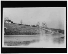 Photo:Curving country road, houses, other buildings in background