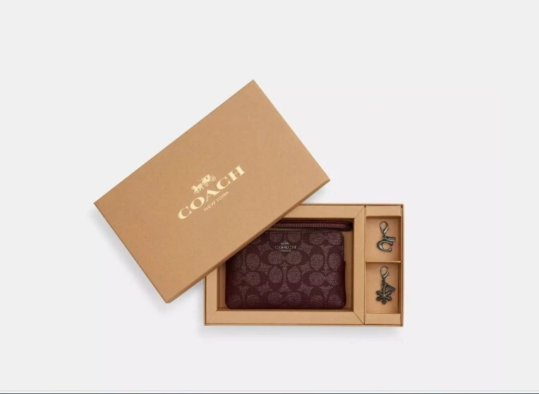 Polsino Coach con zip angolare in scatola in tela firmato con charms. Nuovo con etichetta. Prezzo consigliato $128 00