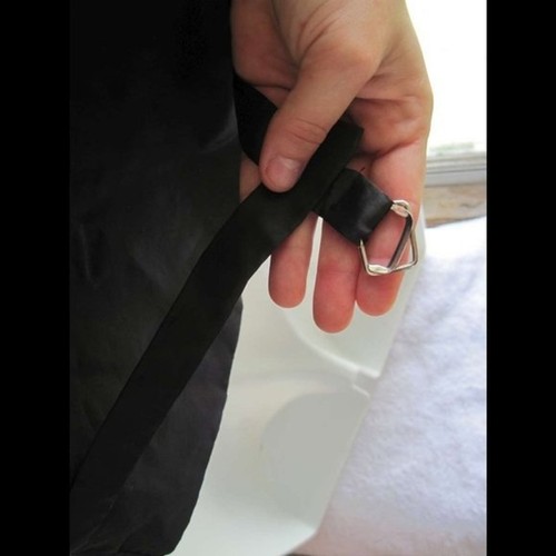 Hand adjusting black dress vest with silver fluted buckle, long black strap, and visible white fabric flaws.